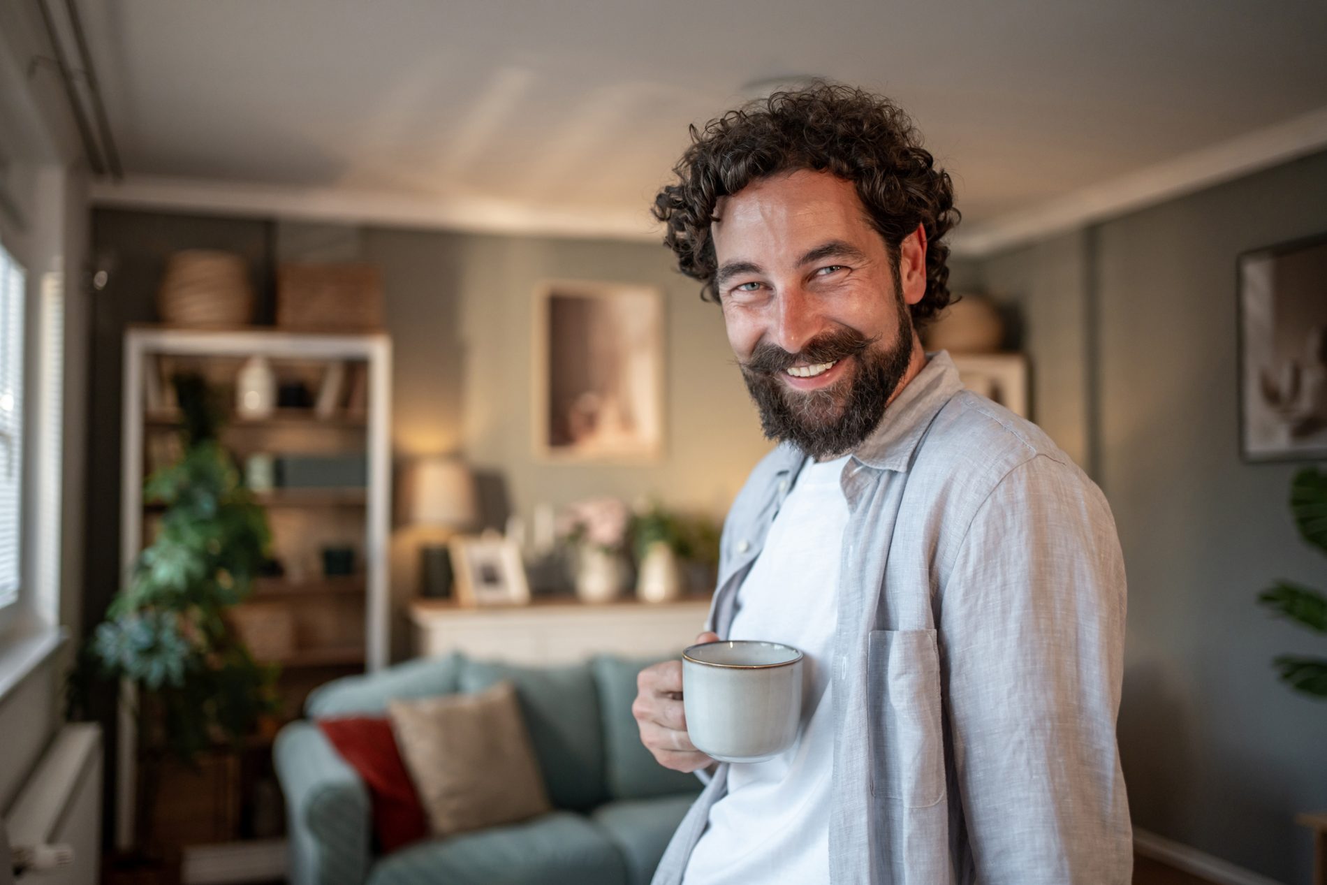 Obraz przedstawiający uśmiechniętego mężczyznę trzymającego kubek z kawą