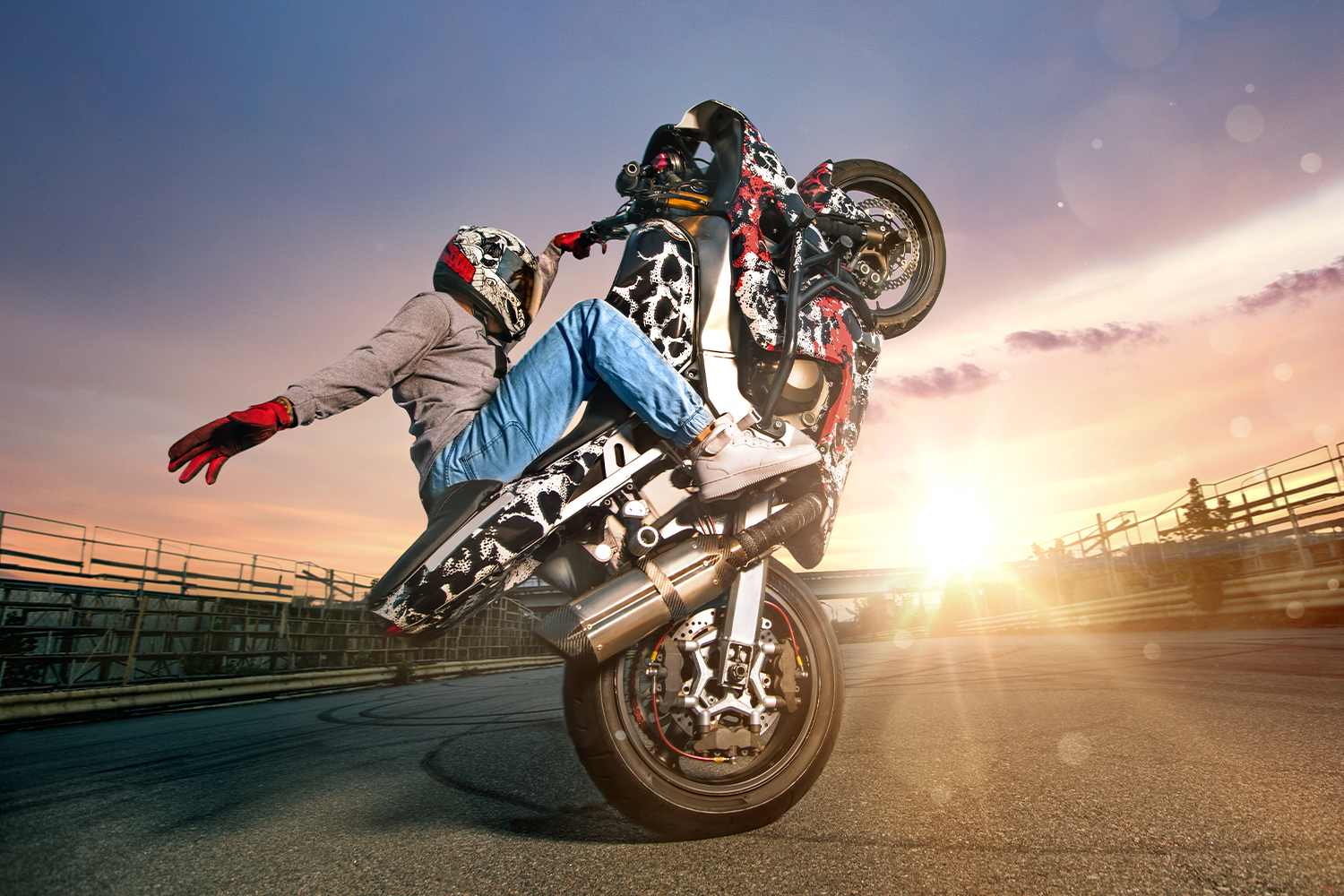 Grafika promująca event Motocykliści dzieciom w M1 Częstochowa. Motocyklista jadący na jednym kole na parkingu.